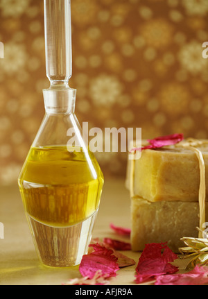 Bottle of oil, natural soaps and petals against a brown floral background Stock Photo