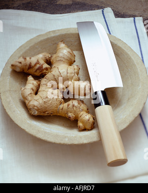 Fresh root ginger on plate with japanese knife and white and blue striped linen cloth Stock Photo