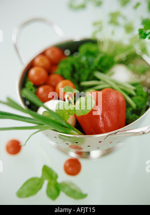 Vegetables and herbs in metal colander Stock Photo