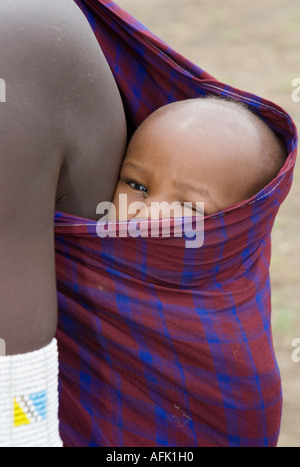 Masai mother carrying child on her back in the forest the Ngorongoro Conservation Area Stock Photo