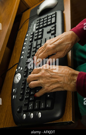 Closeup of senior woman's hands typing on computer keyboard Stock Photo