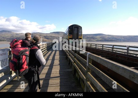 Family Walking across the rail and foot bridge over the Mawddach estuary Barmouth snowdonia Gwynedd North Wales, watching train Stock Photo