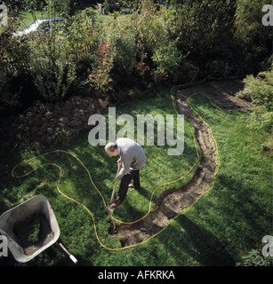 Birds-eye view of man digging new path before paving in lawn Stock Photo