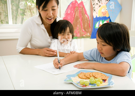 Young Boy Doing Homework with Mom and Brother Helping Stock Photo