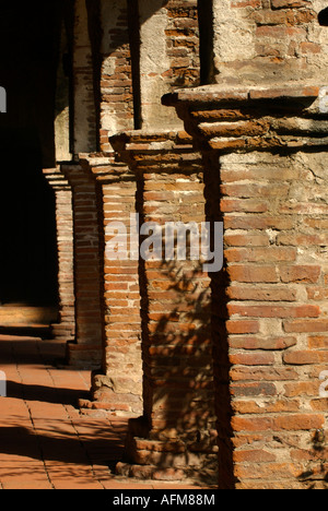 Weathered and worn brick and mortar columns cast shadows on clay tiles at the Mission at San Juan Capistrano, CA, USA Stock Photo