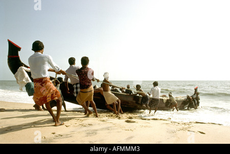 India Kerala Alleppey hauling fishing boat up the beach Stock Photo