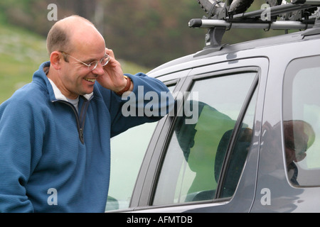 Man leaning on car talking on the mobile phone Stock Photo
