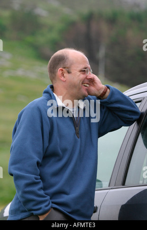 Man leaning on car talking on the mobile phone Stock Photo