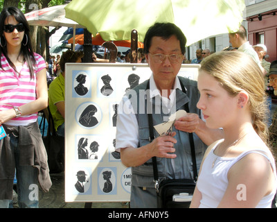 Asian artist cutting silhouette of Caucasian girl in Place du Tertre Montmartre Paris France Stock Photo