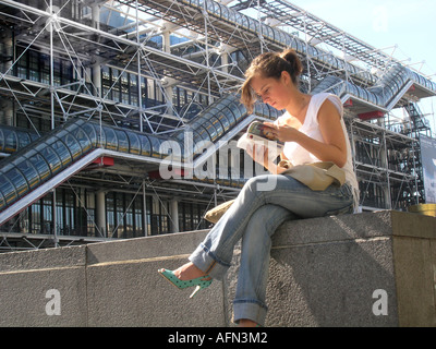 young lady reading book in front of Centre Pompidou Paris France