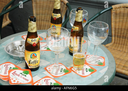 Still life with empty beer glasses and Leffe Blonde beer bottles left behind by guests on cafe table outside Stock Photo