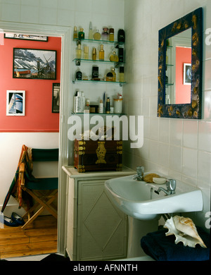 Collection of perfume bottles on glass shelves in corner of small bathroom with door open to the landing Stock Photo