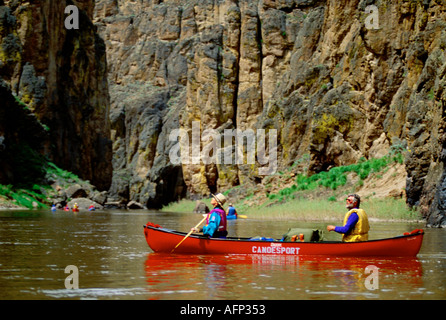 USA Idaho- Oregon East Fork of the Owyhee River paddlers in red canoe going through deep canyon walls The Owyhee Canyonlands Stock Photo