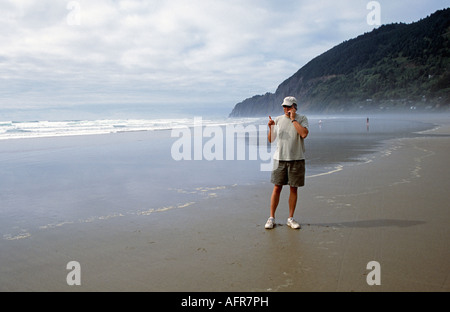 A man talking on a cell phone while on vacation on a beach on the Oregon coast Stock Photo