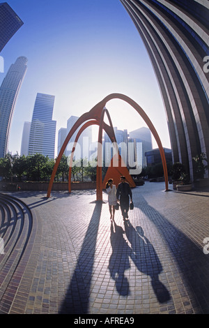 Businessman and woman walking in shadows of Four Arches sculpture designed in 1974 by Alexander Calder in downtown Los Angeles Stock Photo