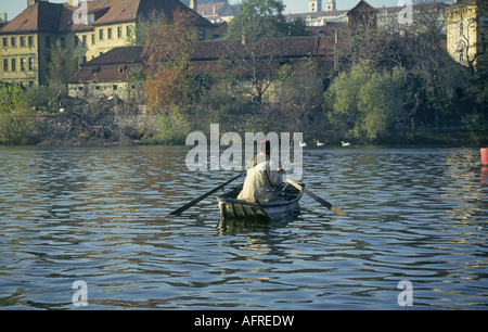 A fisherman is watched by a flock of swans while he fishes on the Vltava River near the Charles Bridge Stock Photo