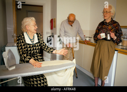 Residents in a residential care home. Doing domestic chores ironing and chatting to other residents. Cirencester Gloucestershire 1990s 1991 UK. Stock Photo