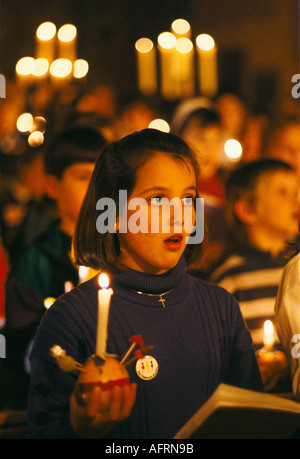 Teen schoolgirl. Christingle Christmas church carol service choir singing. Holding lit candles with orange Leighton Buzzard 1990s UK HOMER SYKES Stock Photo