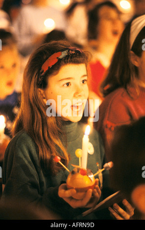 Teen schoolgirl. Christingle Christmas church carol service choir singing. Holding lit candles with orange Leighton Buzzard 1990s UK HOMER SYKES Stock Photo
