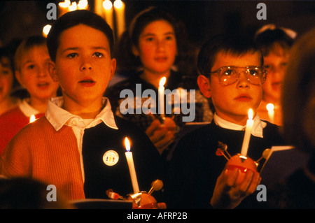 Christingle Christmas church carol service school children choir singing. Holding lit candles with orange Leighton Buzzard 1990s UK HOMER SYKES Stock Photo