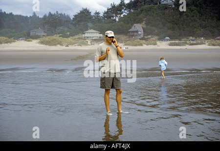 A man talking on a cell phone while on vacation on a beach on the Oregon coast Stock Photo