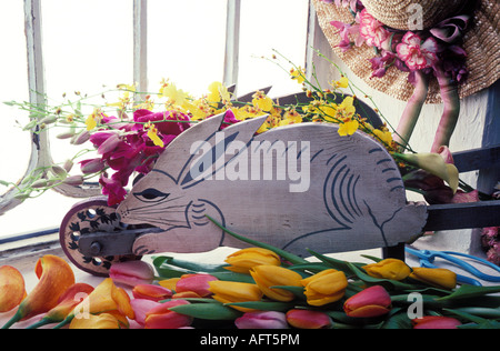 Rabbit wheelbarrow with flowers in window Stock Photo
