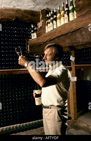 English wine 1980s Somerset. UK Jim Dowling owner of Pilton Manor Vineyard in cellar checking colour and taste white wine from Seyval grapes 1989 UK Stock Photo