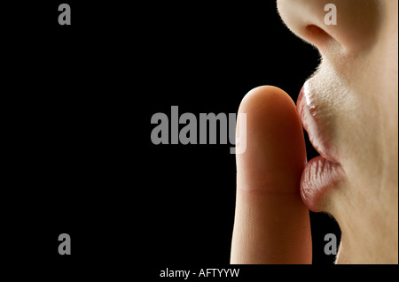 A profile close up of a womans finger pressed to her lips Stock Photo