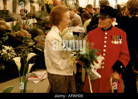 Last day of the Chelsea Flower show 1980s London UK. Visitor and Chelsea Pensioner in red uniform 1984.  HOMER SYKES Stock Photo