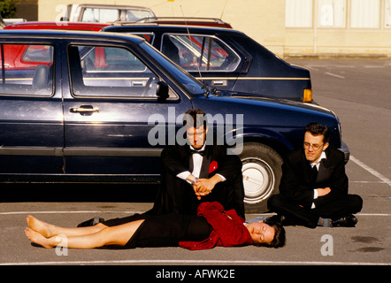 Morning After The Night Before 1990s May Ball UK. Men watch over female companion lying asleep car Royal Agricultural College Cirencester HOMER SYKES Stock Photo