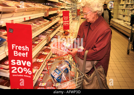 Older woman making a choice in her local supermarket. Meat Counter. Fresh Beef checking prices 1990s London UK HOMER SYKES Stock Photo
