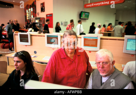 WWW Internet cafe London UK 1990s. Elderly couple using computers, new technology. Customers background queue up for cafe service. 1999 England Stock Photo