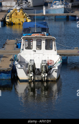 small white fishing boat with dual outboard motors sitting moored in Ballycastle marina on a calm day Stock Photo