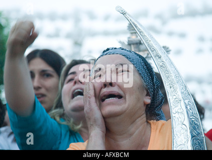 Moved women carrying Virgin holy valuables as vow praise Virgin image and cry Stock Photo