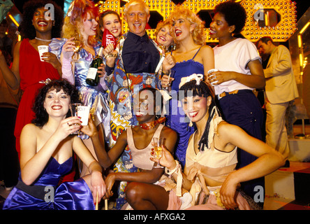 Jimmy Savile British BBC TV presenter radio disc jockey with Top Of The Pops group of dancers gather around Saville. 1980s UK HOMER SYKES Stock Photo