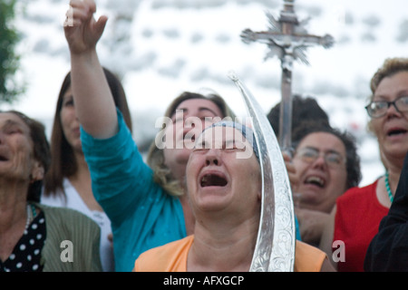 Moved women carrying Virgin holy valuables as vow praise Virgin image and cry Stock Photo