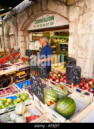 Vence on the Côte d'Azur, France - old quarter shop owner refills fruit and vegetables on epicerie market stall Stock Photo