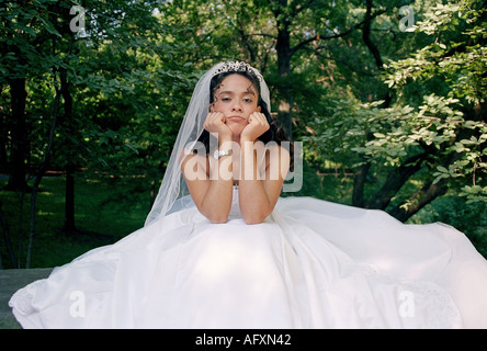 A young bride in a lovely wedding dress sitting down and looking sad and lonely Stock Photo