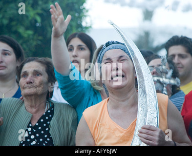 Moved women carrying Virgin holy valuables as vow praise Virgin image and cry Stock Photo