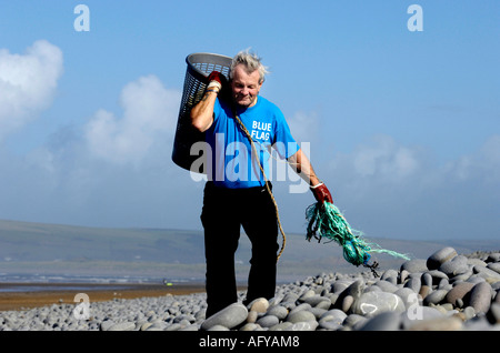 active tidy beach campaigner Les Garland collecting rubbish at Westward Ho! pebble beach North Devon UK Stock Photo