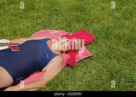 Adult sunbather lying on grass with her eyes covered Stock Photo