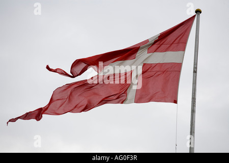 Danish Flag Banner A Danish flag flying in a stiff wind against a white sky Kronborg Castle Helsingor near Copenhagen Denmark Stock Photo