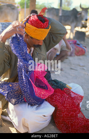 Man tying a brightly coloured turban on the street, Jaisalmer, Rajasthan, India Stock Photo