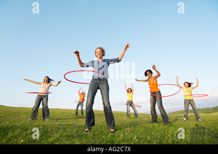 Group of friends using hula hoops in mountain field, low angle view Stock Photo