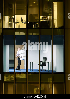 Office worker carrying boxes in office, view from building exterior Stock Photo