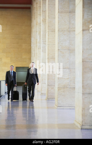 Two business men pulling luggage in airport lobby Stock Photo