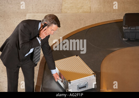 Business man claiming suitcase at luggage carousel in airport Stock Photo
