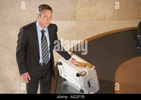 Business man claiming suitcase at luggage carousel in airport Stock Photo