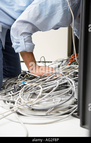 Man working on tangle of computer wires in office Stock Photo
