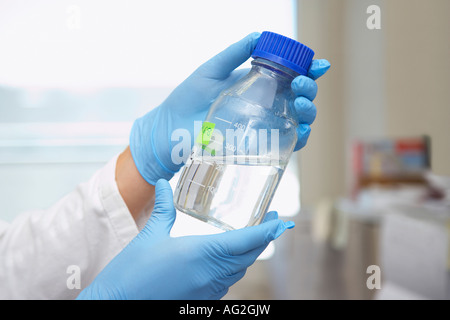 Chemist holding bottle of solution in laboratory, close-up of hands Stock Photo